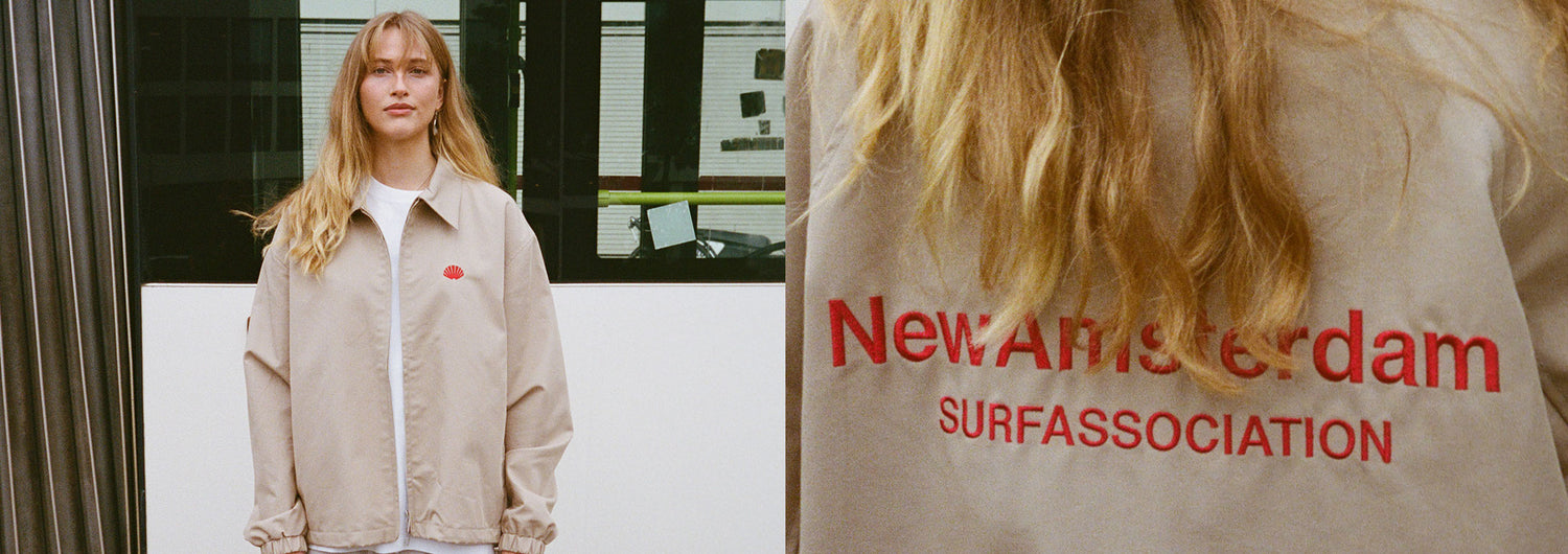 Zweiteiliges Bild. Links, eine junge Frau steht vor einem Bus und trägt ein beige New Amsterdam Jacke. Rechts, der rote Print auf Rückseite der Jacke, mit der Aufschrift New Amsterdam in Großaufnahme. 